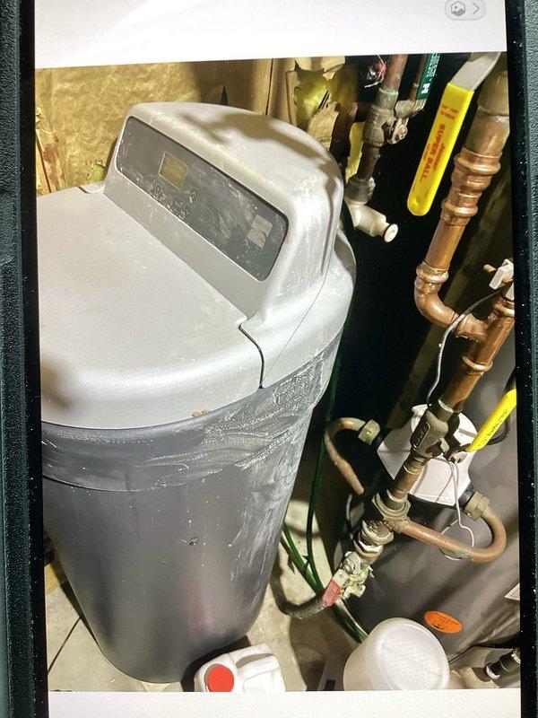 Responded to service call for non-functioning water softener unit that was over 10 years old. Upon inspection, determined that the existing gray cylindrical softener unit with moisture present on exterior had failed beyond economical repair due to age and condition. Recommended and discussed full system replacement with customer, as repair was not feasible given the unit's age and extent of deterioration.