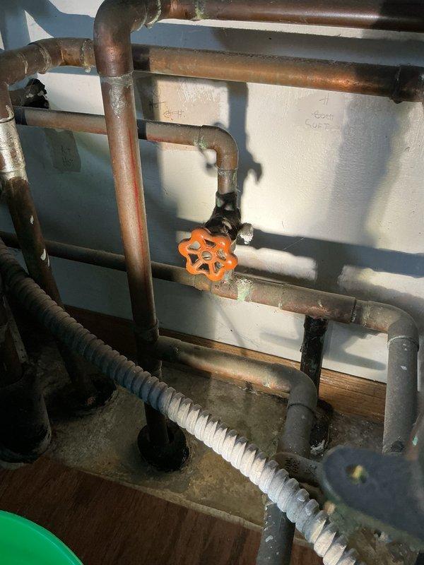 Responded to a pinhole leak in copper piping located in the utility room mechanical area. Upon inspection, identified a small leak in the copper line and observed widespread corrosion throughout the copper piping system and fittings, indicating advanced aging of the plumbing infrastructure. The existing system includes a water filtration unit with pressure regulation components, multiple copper supply lines, and various valve assemblies showing signs of oxidation and patina buildup.

Performed immediate repair of the active pinhole leak to stop water intrusion and restore system integrity. Documented the extensive corrosion present on copper pipes and fittings throughout the mechanical room for follow-up evaluation. Recommended comprehensive assessment for potential re-piping of remaining copper lines due to the deteriorated condition of the existing plumbing system to prevent future failures.