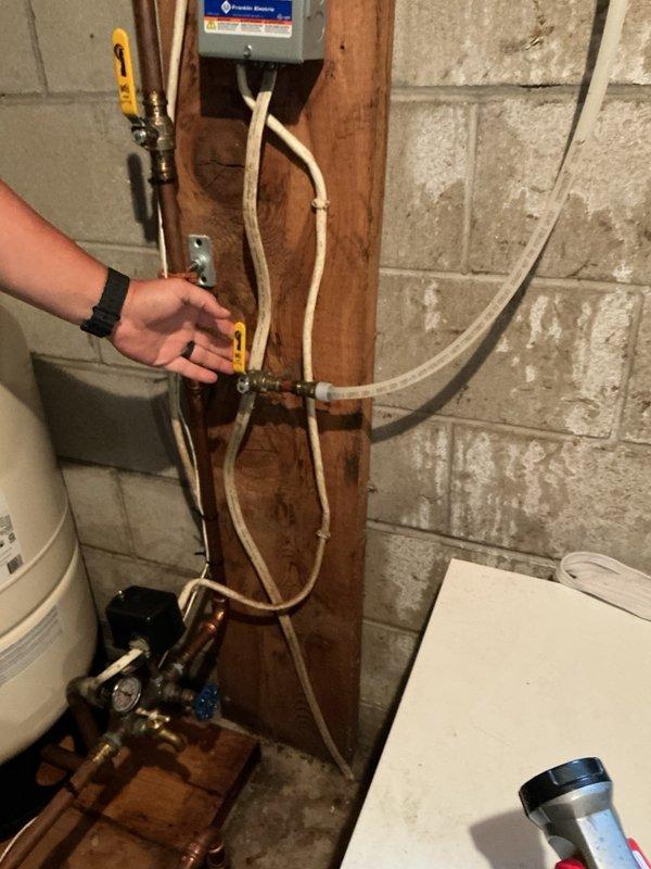 Responded to callback regarding pressure tank installed in March. Customer reported high electric bills and continuous running when secondary valve was open, with wet spot appearing in area. Upon inspection, identified secondary valve as feed line for geothermal system. Explained valve function and confirmed customer's observation that system operates correctly at 70 PSI with secondary valve closed. Advised customer to keep secondary valve in closed position as previously configured. Verified wet spot resolved with valve closure and confirmed proper tank pressurization. Documented installation with photos showing pressure tank assembly, copper piping connections, valve configuration, and geothermal feed line. No further adjustments required.