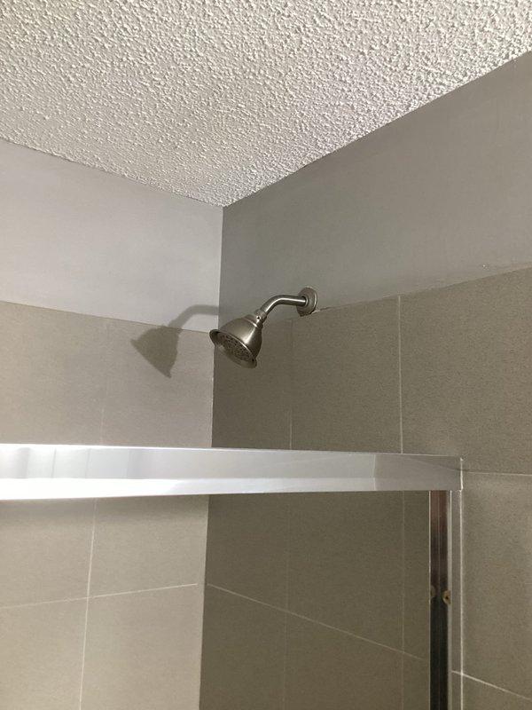 Installed customer-supplied shower trim kit in bathroom with beige speckled tile surround. Completed installation of chrome single-handle shower valve control with circular escutcheon plate and matching chrome tub spout below, both fixtures mounted on tiled wall above existing bathtub. All components secured properly and tested for functionality, with polished chrome finish ensuring consistent appearance throughout the installation.