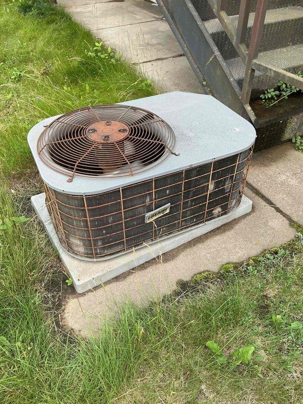 Responded to no-cooling complaint at commercial property where upstairs rooms were not maintaining temperature on hot days. Upon arrival, confirmed adequate airflow at supply vents and that filter had been recently replaced. Inspected outdoor condensing unit and found heavy dirt accumulation and severely clogged condenser coil. Shut down system and performed electrical component inspection; capacitor tested within acceptable range. Thoroughly cleaned and rinsed condenser coil, removing significant debris buildup that was restricting airflow and reducing heat transfer efficiency. Restarted system and performed refrigerant pressure check with manifold gauges; pressures indicated proper charge levels. Verified unit returned to normal cooling operation after cleaning. Identified thermostat location issue as contributing factor to comfort complaints—thermostat positioned in downstairs break room which runs cooler than larger upstairs spaces, causing premature system shutdown before upstairs