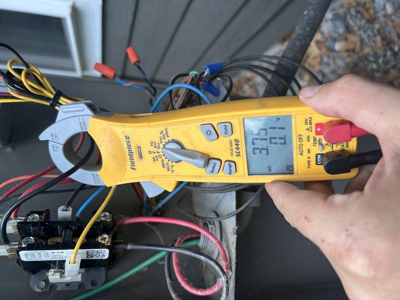 Responded to no cooling complaint on seven-year-old two-stage system with elevated indoor humidity. Diagnosed system operating normally on first stage cooling (Y1), but second stage (Y2) failing to activate. Verified 24V power present at Y2 terminal and confirmed solenoid clicking sound at compressor when second stage called, indicating electrical signal reaching unit but compressor not engaging. Used multimeter to verify voltage and monitored amperage at outdoor unit—no increase in amp draw when transitioning to second stage. Checked refrigerant pressures which remained unchanged between stage one and stage two operation, confirming compressor not running. Attempted mechanical troubleshooting of solenoid valve without success. Determined compressor internal solenoid valve failure preventing second stage operation. Documented findings with photos of electrical testing and compressor components showing age-related corrosion. Recommended compressor replacement under manufacturer warranty
