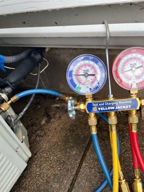 Completed comprehensive tune-up on both furnace and air conditioning system. Inspected all routine furnace components including heat exchanger, gas pressures, and flue passages—all found within manufacturer specifications. Furnace operated properly with approximately 50-degree temperature drop across heat exchanger. 

On the air conditioning side, discovered heavily plugged condenser coil restricting airflow and completely blocked evaporator drain line that had been causing water leakage. Cleared evaporator drain line to restore proper condensate drainage. AC unit achieved approximately 20-degree temperature drop during extended operational test, though refrigerant charge appears low on R22 system. Both systems ran for 10-15 minutes to verify proper operation under load.

Documented findings with photos showing blower assembly with heat damage indicators and HVAC testing equipment setup used for system diagnostics. Provided estimates for recommended repairs including condenser coil cle