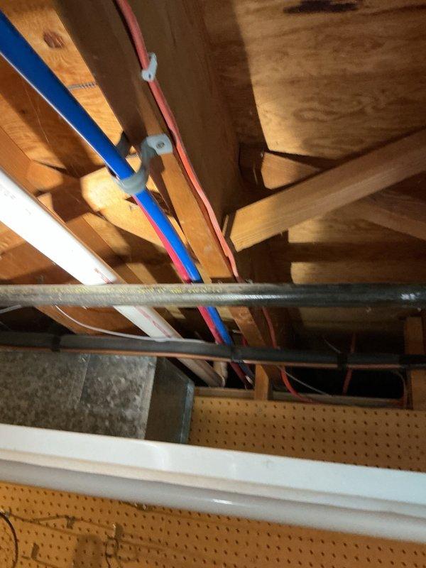 Responded to complaint of gurgling noises from toilet when shower was in use in basement bathroom. Upon inspection, identified improper venting throughout the plumbing system resulting from previous remodeling work. Examined exposed plumbing infrastructure in ceiling area, including PVC drain lines and vent piping configuration. Determined that drain-waste-vent system was not installed to code specifications, causing negative air pressure and gurgling sounds during fixture use. Documented existing conditions with photographs showing inadequate venting arrangement and improper trap configuration. Recommended complete re-piping and proper venting installation to resolve drainage issues and bring system up to code compliance.