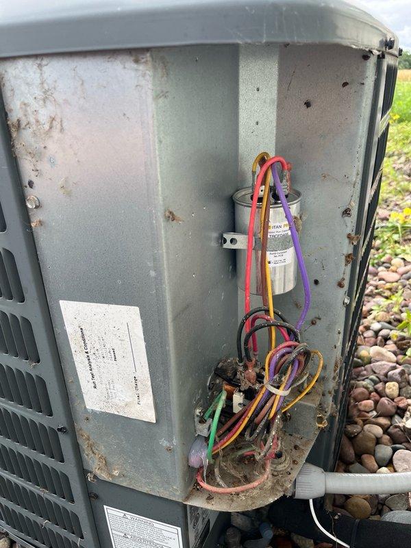 Responded to no cooling complaint on 13-year-old central air conditioning system. Upon arrival, found outdoor unit condenser fan motor operating but compressor not running. Diagnosed failed dual run capacitor with readings of 0 microfarads on compressor (HERM) terminal and approximately 2 microfarads on fan terminal, significantly below rated 40/5 microfarad specification.

Replaced defective capacitor with new dual run capacitor. Removed rodent intrusion (mice) from electrical cabinet and sealed wire entry penetrations with silicone to prevent future pest access. Cycled system through complete cooling operation and verified proper compressor engagement, condenser fan operation, and airflow. Measured 15-20 degree temperature split across evaporator coil, confirming system restored to normal cooling capacity.