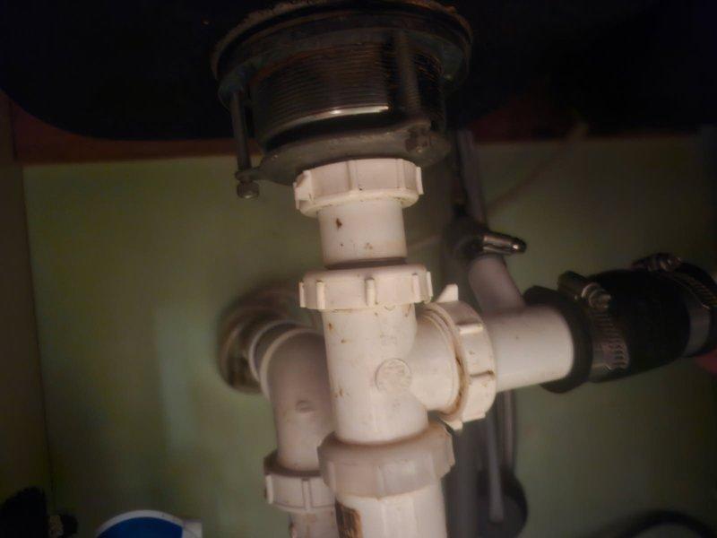 Responded to a kitchen sink drain leak caused by a loose PVC connection under the basin. Upon inspection, found the drain assembly fittings had worked loose and required replacement. Additionally, installed a customer-provided kitchen sink, which necessitated lowering the drain line to accommodate the new fixture's configuration. Replaced the deteriorated PVC drain assembly components, including slip joints and trap fittings, ensuring proper alignment and secure connections. All connections were tested for leaks and confirmed watertight upon completion.
