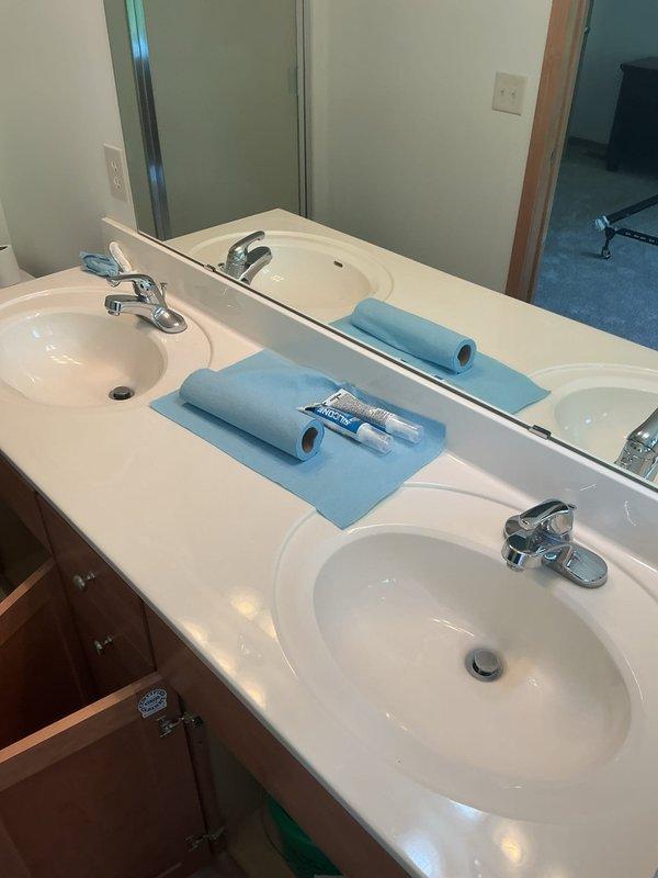 Installed three new chrome vanity faucets with drain stems on double sink bathroom vanity in vacant property. Diagnosed and repaired refrigerator water line leak caused by faulty coupling, replaced defective coupling with new fitting, and restored water supply to appliance. Verified all fixtures operational and confirmed completion of work order items prior to departure.