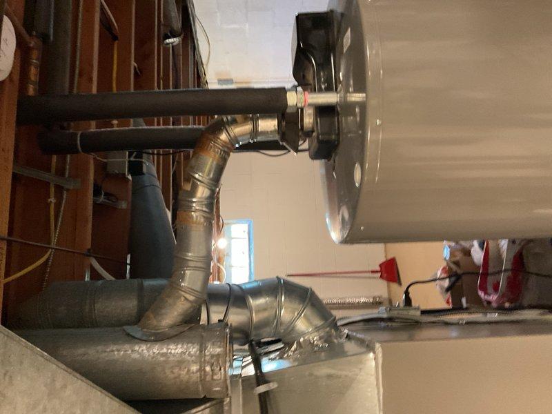 Responded to service call regarding water heater venting concerns and carbon monoxide alarm activation. Upon inspection, observed condensate accumulation at B-vent cap connected to atmospheric natural-draft water heater. Identified orphaned vent/chimney condition resulting from previous furnace upgrade from 80% efficiency to 96% high-efficiency unit, leaving water heater as sole appliance venting through oversized chimney. This configuration allows flue gases to cool prematurely, causing condensation and potential backdrafting at draft hood, particularly under negative pressure conditions. Documented moisture presence in venting system and confirmed prior spillage events reported by occupant. Performed preliminary visual inspection of venting components and HVAC system with air conditioning operating and building closed. Photographed ductwork installation and system configuration for documentation. Recommended comprehensive follow-up visit to conduct combustion appliance zone depressur