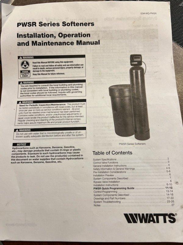 Responded to a PWSR Series water softener continuously draining into floor drain. Attempted troubleshooting by cycling through regeneration process and testing bypass function, but unit continued to drain improperly. Diagnosed system as requiring replacement due to persistent malfunction that could not be resolved through standard repair procedures. Documented existing installation and reviewed equipment specifications for replacement unit recommendation.