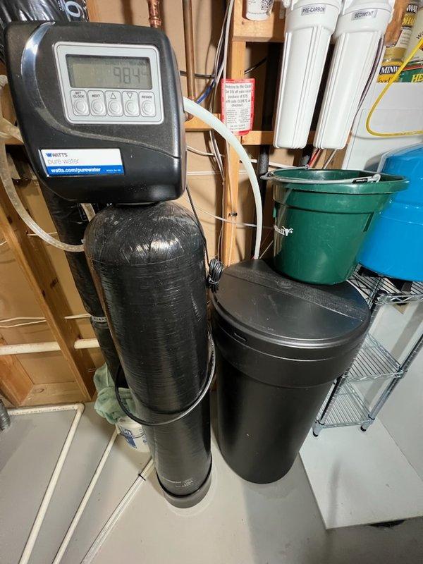 Responded to a PWSR Series water softener continuously draining into floor drain. Attempted troubleshooting by cycling through regeneration process and testing bypass function, but unit continued to drain improperly. Diagnosed system as requiring replacement due to persistent malfunction that could not be resolved through standard repair procedures. Documented existing installation and reviewed equipment specifications for replacement unit recommendation.