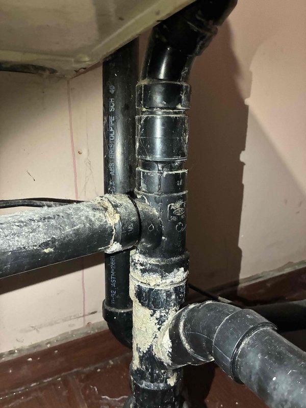 Responded to water leak in basement laundry room where ABS Schedule 40 drainage pipe entering floor showed active leak with visible mineral deposits and efflorescence buildup on pipe surfaces and connections. Documented conditions with photos showing deteriorated pipe configuration and provided written estimate to property owner for necessary repairs to compromised drainage system.