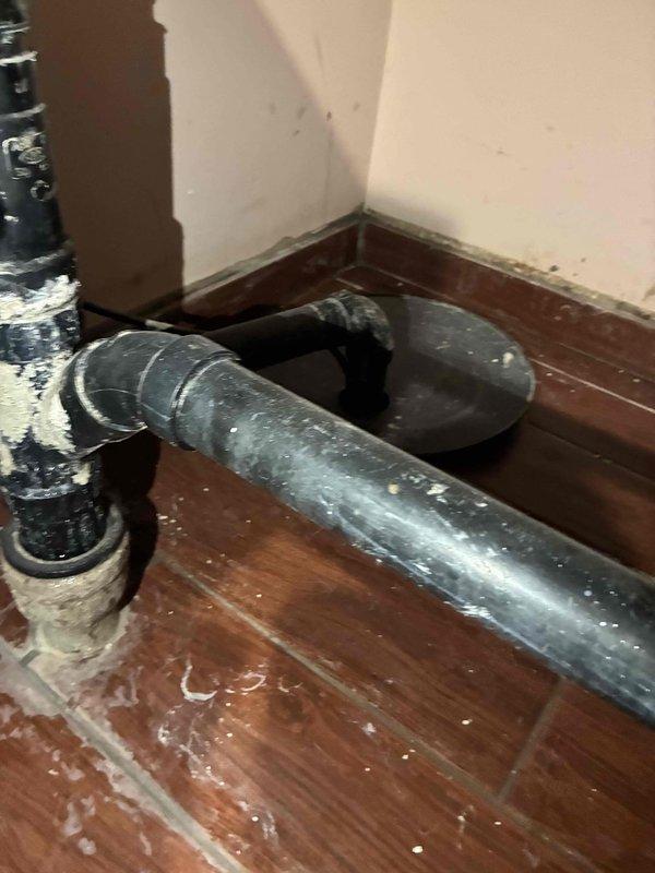 Responded to water leak in basement laundry room where ABS Schedule 40 drainage pipe entering floor showed active leak with visible mineral deposits and efflorescence buildup on pipe surfaces and connections. Documented conditions with photos showing deteriorated pipe configuration and provided written estimate to property owner for necessary repairs to compromised drainage system.