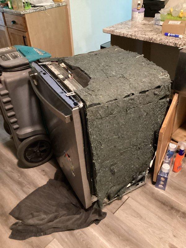 Responded to water leak emergency with mitigation crew already on-site. Diagnosed dishwasher as the source of active water leak affecting kitchen flooring. Upon inspection, found dishwasher pump had failed, causing water to discharge onto floor rather than drain properly. Unit exhibited heavy accumulation of lint and debris on exterior components and housing, indicating age and lack of maintenance. Verified internal components showed water pooling in bottom basin with compromised drainage system. Pulled appliance from cabinet opening to fully assess leak source and extent of damage. Confirmed pump assembly failure as primary cause of water intrusion. Documented conditions with photographic evidence for insurance claim purposes. Recommended complete dishwasher replacement due to pump failure and overall deteriorated condition of unit.