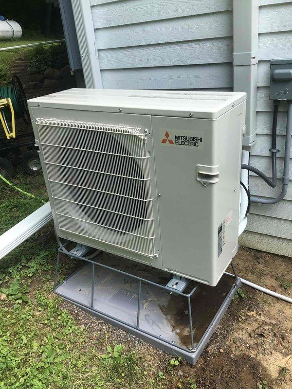 Responded to warranty call for 12-5 Mitsubishi mini split system installed two months prior with water leaking from indoor unit on east side of home. Inspected system and traced issue to improper condensate drainage at outdoor unit. Found condensate line had improper pitch with upward curve causing water backup. Cut back approximately one foot of exterior condensate line to establish proper downward slope for gravity drainage. System drained accumulated water for approximately one minute and indoor unit leak resolved. Verified proper drainage operation and system returned to normal function.