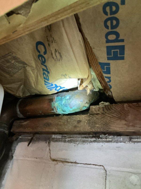 Responded to water leak emergency with moisture intrusion affecting multiple levels of the residence. Upon investigation, identified failed toilet wax ring seal in upper-level bathroom as primary source of water infiltration, causing damage to ceiling materials and visible moisture migration into garage area below. Observed significant corrosion and oxidation on copper supply lines passing through structural framing, indicating prolonged exposure to moisture. Documented extensive deterioration of surrounding building materials, including damaged subflooring and ceiling penetration points where plumbing fixtures penetrate. Replaced defective wax ring seal on toilet to restore proper watertight connection between fixture and drain flange. Inspected all associated plumbing connections for additional leaks or compromised seals. Coordinated with water damage restoration services for remediation of affected areas.