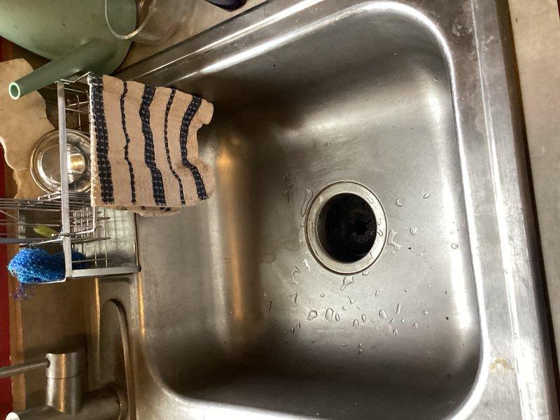 Responded to clogged kitchen sink with water backup that had sprayed beneath the cabinet. Removed existing plug-in garbage disposal unit per homeowner request, as dishwasher drain line was independently plumbed. Snaked kitchen drain line to clear obstruction and restore proper drainage. Installed standard sink basket strainer assembly to replace disposal opening, ensuring proper seal and functionality. Tested drainage flow and verified no leaks at connections. Left work area clean with sink fully operational.