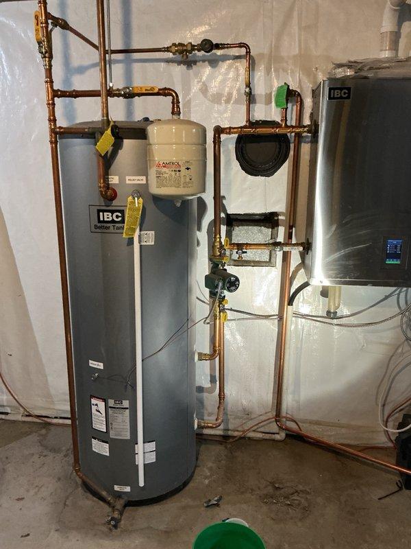 Replaced IBC indirect water heater tank under manufacturer parts warranty, including complete removal and disposal of failed unit. During system restoration, the backflow preventer began leaking upon water supply activation, requiring immediate replacement with new brass backflow prevention device. Installed new indirect water heater with expansion tank, connected all copper piping, and verified proper integration with existing IBC boiler system. Purged air from hydronic heating system, tested all heating zones for proper operation, and confirmed system pressure stabilized at 22 PSI. All components functioning within normal parameters upon completion.