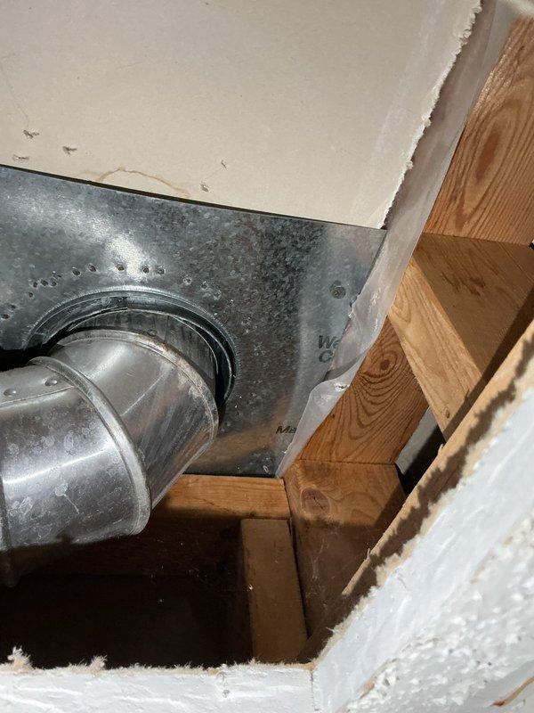 Responded to water leak investigation in mechanical room ceiling. Previous HVAC contractor had determined leak was not originating from furnace system. Upon arrival, performed visual inspection of affected ceiling area and accessed ceiling cavity to diagnose water source. Cut access opening in drywall to expose plumbing lines and HVAC ductwork above mechanical room. Thoroughly inspected all visible plumbing connections, supply lines, and drain lines within the ceiling cavity. Examined galvanized HVAC ductwork and transitions for signs of condensation or moisture accumulation. Confirmed that plumbing system was not the source of the water leak. Documented conditions with photographs showing ductwork installation, wooden framing, and ceiling cavity components for further investigation by appropriate trade contractor.