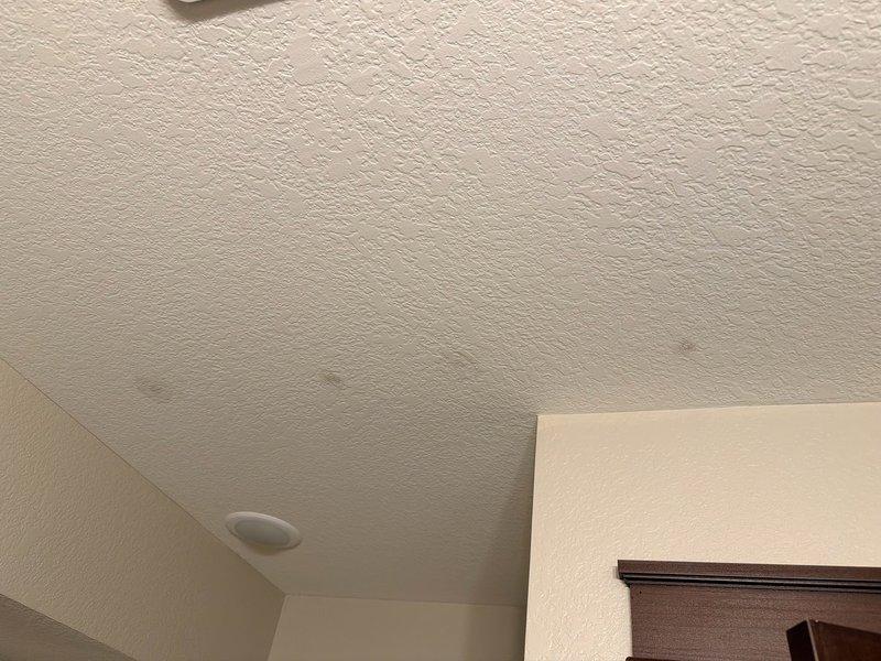 Responded to report of water leaking from upstairs bathroom onto lower level ceiling. Upon arrival, conducted thorough inspection of affected area and found small drip marks on ceiling but no active water leakage present at time of service call. Examined plumbing layout and determined no water supply or drain lines located directly above the stained area. Assessed potential sources including nearby kitchen and dishwasher plumbing approximately 6-8 feet away, which would route toward laundry room rather than affected location. Evaluated possibility of condensation from nearby sprinkler line as likely cause of moisture marks. Documented conditions with photographs showing textured ceiling with minor staining and no active water damage. Advised property owner on multiple monitoring points to watch for future occurrences and provided guidance on identifying potential leak sources. Recommended continued observation of area to determine if issue recurs or if condensation pattern develops.
