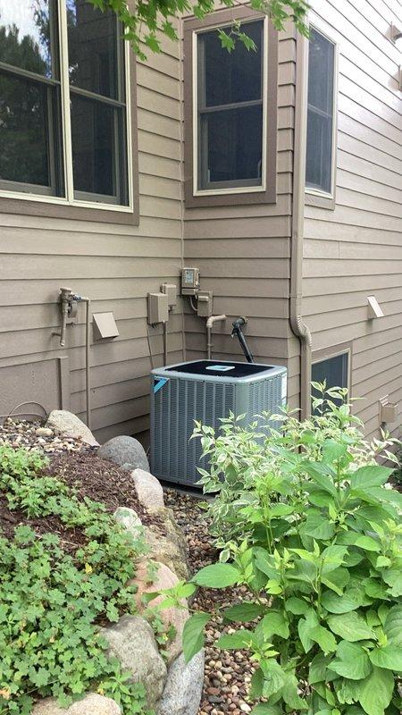 Responded to no cooling complaint on residential air conditioning system with previous compressor replacement history. Upon arrival, found compressor locked and inoperable despite condenser fan motor functioning properly. Compressor housing was excessively hot to touch, indicating mechanical failure. Performed coil cleaning and attempted to cool compressor housing with water to rule out thermal overload. Unable to cycle equipment or restore system operation. Documented equipment condition with photos showing outdoor condensing unit installation and surrounding area. System requires compressor or complete condenser replacement under warranty coverage.