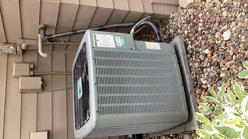 Responded to no cooling complaint on residential air conditioning system with previous compressor replacement history. Upon arrival, found compressor locked and inoperable despite condenser fan motor functioning properly. Compressor housing was excessively hot to touch, indicating mechanical failure. Performed coil cleaning and attempted to cool compressor housing with water to rule out thermal overload. Unable to cycle equipment or restore system operation. Documented equipment condition with photos showing outdoor condensing unit installation and surrounding area. System requires compressor or complete condenser replacement under warranty coverage.