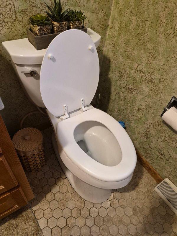 Responded to service call for non-functioning toilet with reported leak at base. Upon inspection, identified failed wax ring seal and deteriorated toilet flange causing water seepage onto bathroom floor. Documented extensive corrosion on flange and surrounding plumbing components, including mineral buildup on visible pipe connections beneath fixture. Provided estimate for complete flange replacement and toilet reinstallation with new wax ring seal to restore proper function and prevent further water damage to subfloor.