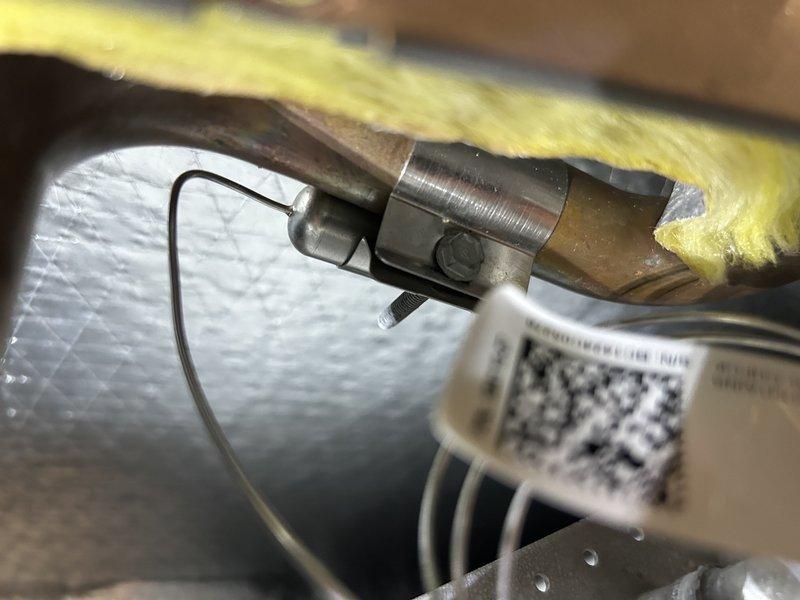 Responded to repeat no-cool complaint with system freezing and water accumulation at furnace. Upon arrival, verified coils were clean and air filter was new. Placed system in charge mode and confirmed refrigerant charge was adequate with 12° subcooling. Identified root cause as insufficient airflow—thermostat settings showed maximum airflow for high cooling below 1200 CFM. Adjusted airflow parameters in thermostat for high cooling, low cooling, and dehumidification modes to proper levels. Tested system operation in all cooling modes and confirmed low-side pressure remained above freezing saturation temperature, eliminating freeze-up condition. Addressed secondary issue of condensate pump discharge line leak by installing hose clamp at connection point, which stopped water leakage. System operating normally with proper airflow and no freezing upon departure.