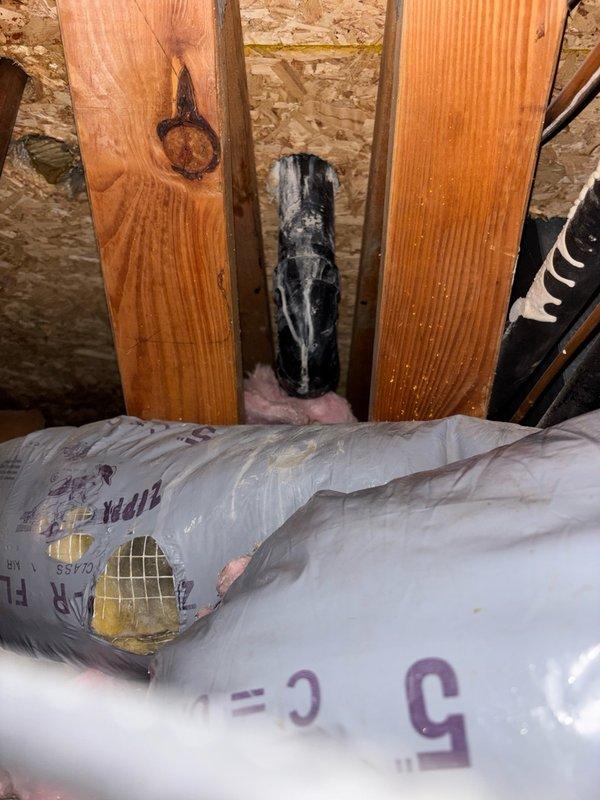 Responded to callback for water leak originating from upstairs unit causing damage to downstairs closet space. Initial concern was toilet leak from upstairs master bathroom. Conducted thorough diagnostic testing in coordination with mitigation crew, running all plumbing fixtures including toilet (5+ flushes), shower, and lavatory faucets for 5-10 minutes with no leaks detected. 

Upon further investigation, identified source as improperly installed AC condensation drain line connected to shared ABS drain pipe that also services water heater T&P valve and humidifier drain. Discovered drain hose was not fully inserted into the ABS drain pipe, causing condensate to discharge on exterior of pipe and onto ductwork below, resulting in water infiltration into lower unit's closet space.

Corrected issue by removing existing drain hose and installing longer replacement hose to ensure proper insertion into drain pipe interior. Secured new hose connection to existing drain assembly. Verified repa