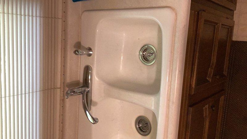 Responded to service call for leaking kitchen sink faucet. Upon inspection, identified multiple leak sources including a malfunctioning Moen side sprayer and a faulty strainer in the right sink compartment. Removed and replaced the defective side sprayer with new Moen unit, ensuring proper connection and seal. Installed new twist and lock strainer assembly in right basin to eliminate leak at drain. Tested all components for proper operation and verified no additional leaks present at faucet, sprayer, or drain assemblies upon completion.