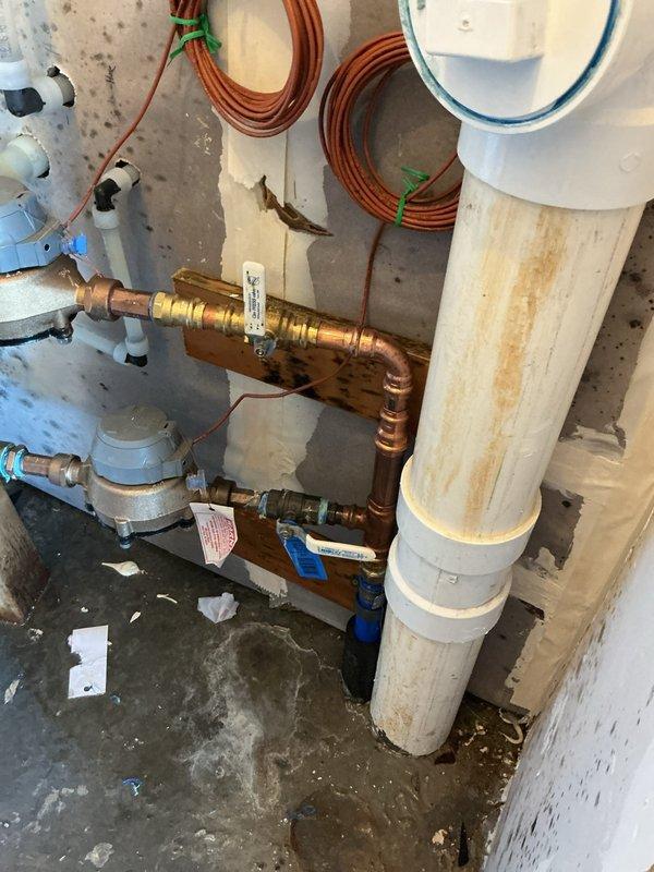 Responded to emergency water leak in mechanical room located at the main service line entry point. Upon arrival, city water had already been shut off due to active leak. Identified failed threaded ball valve on main house shut-off valve just before entry to residence. Replaced defective main shut-off ball valve and restored water service to property. During system pressurization testing, discovered secondary failure at irrigation system ball valve on same service line. Shut down water supply again and replaced failed irrigation ball valve to complete repairs. Both copper pipe connections were secured with proper fittings and tested for leaks. Visual inspection confirmed significant water damage to mechanical room walls and flooring from the leak. All plumbing connections verified operational before final restoration of water service to home and irrigation system.