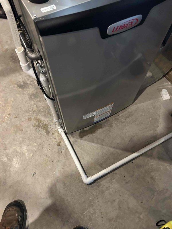 Responded to report of water leaking from Lennox furnace/air handler unit installed previous fall, with significant puddle forming in basement. Upon inspection, identified blockage in condensate drain system preventing proper drainage from drain pan. Removed packing foam and debris from drain pan that was obstructing water flow. Cleared blockage in PVC condensate drain line, restoring proper drainage function. Verified water was draining correctly through white PVC piping system after clearing obstruction. Unit returned to normal operation with no further water accumulation observed.