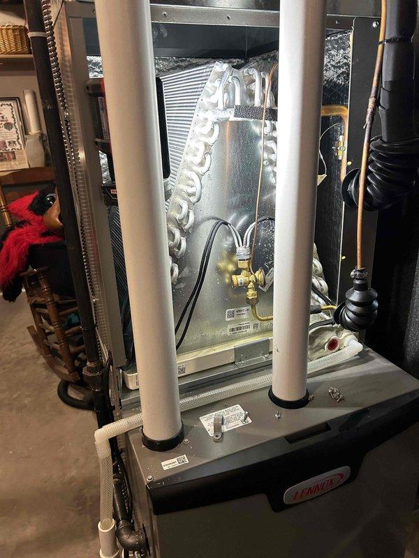 Responded to report of water leaking from Lennox furnace/air handler unit installed previous fall, with significant puddle forming in basement. Upon inspection, identified blockage in condensate drain system preventing proper drainage from drain pan. Removed packing foam and debris from drain pan that was obstructing water flow. Cleared blockage in PVC condensate drain line, restoring proper drainage function. Verified water was draining correctly through white PVC piping system after clearing obstruction. Unit returned to normal operation with no further water accumulation observed.