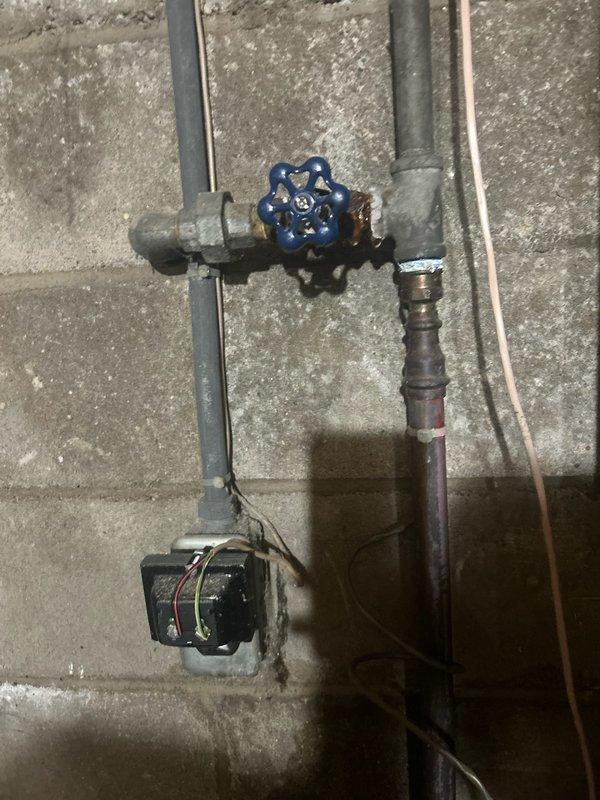 Responded to emergency water leak in basement where deteriorating 1/2 inch galvanized pipe near shut-off valve was dripping onto electrical wiring, creating smoke and gas odor. Shut off water supply to home and assessed the galvanized supply line feeding the 4-bathroom residence, which showed significant corrosion and rot throughout. Removed and replaced 30 feet of failing 1/2 inch galvanized pipe with new piping, extending from the main shut-off valve to the water treatment system. Installed new shut-off valve with pressure monitoring device and ensured proper connections to existing copper distribution lines. Tested system for leaks and restored water service to home.