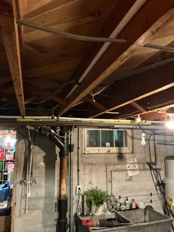 Responded to emergency water leak in basement where deteriorating 1/2 inch galvanized pipe near shut-off valve was dripping onto electrical wiring, creating smoke and gas odor. Shut off water supply to home and assessed the galvanized supply line feeding the 4-bathroom residence, which showed significant corrosion and rot throughout. Removed and replaced 30 feet of failing 1/2 inch galvanized pipe with new piping, extending from the main shut-off valve to the water treatment system. Installed new shut-off valve with pressure monitoring device and ensured proper connections to existing copper distribution lines. Tested system for leaks and restored water service to home.