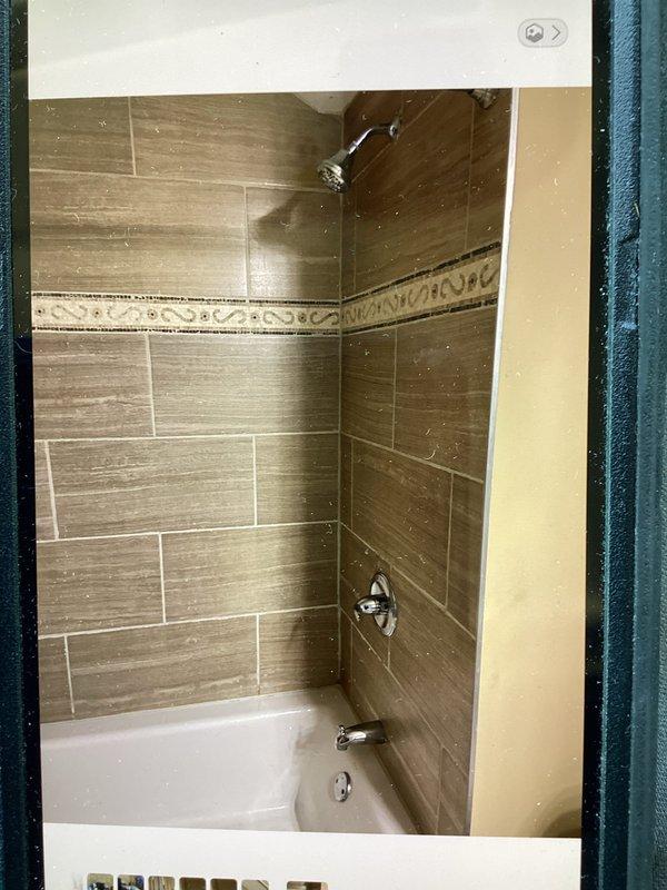 Replaced defective shower valve and trim kit in bathroom tub/shower combination. Installed Moen L2352 chrome shower control valve with single-lever handle, shower arm and head, and tub spout. New fixtures feature Scald-Guard temperature limiting technology and water-saving design. All components secured to existing tile wall with wood-grain pattern and properly sealed. System tested for proper operation, temperature control, and leak-free performance.
