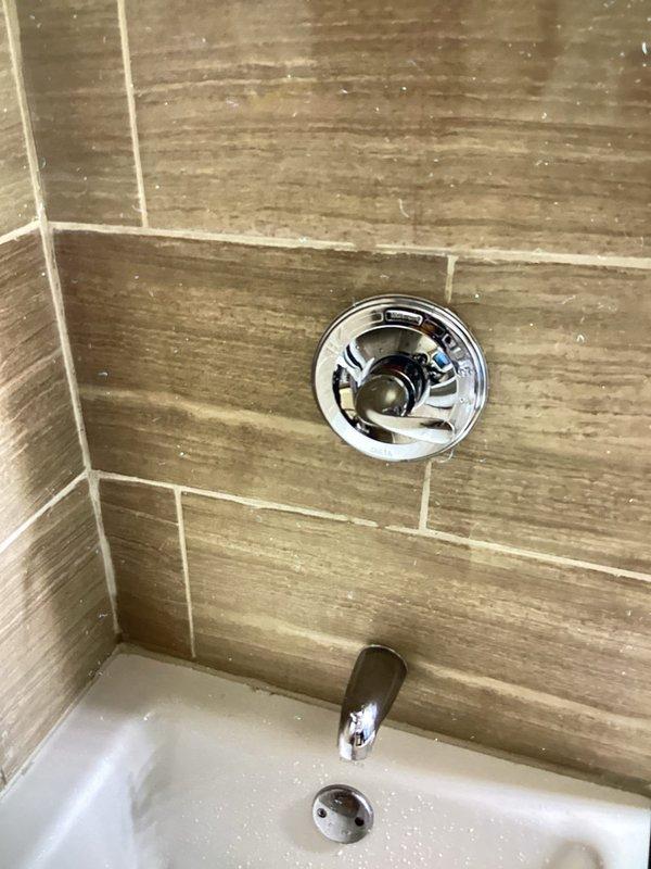 Replaced defective shower valve and trim kit in bathroom tub/shower combination. Installed Moen L2352 chrome shower control valve with single-lever handle, shower arm and head, and tub spout. New fixtures feature Scald-Guard temperature limiting technology and water-saving design. All components secured to existing tile wall with wood-grain pattern and properly sealed. System tested for proper operation, temperature control, and leak-free performance.