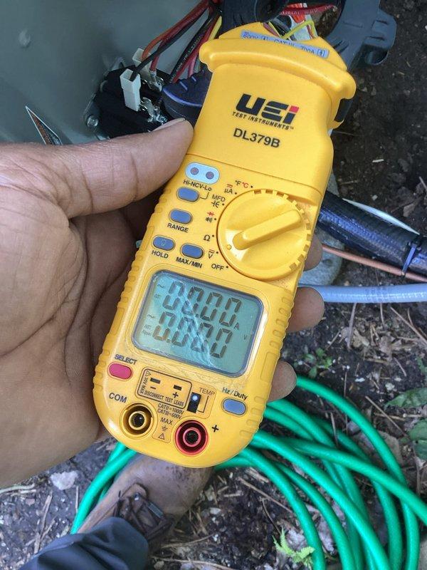 Responded to no cooling complaint on warranty system with recurring refrigerant loss. Unit exhibited short cycling behavior, running approximately 10 seconds with 10-minute intervals between cycles. Performed leak search using UV dye previously added during prior service visit. Successfully located refrigerant leak at valve assembly. Documented findings with photos showing leak location at brass valve connection and recorded system measurements with digital multimeter. Completed warranty correction form for leak repair authorization. System requires refrigerant leak repair to restore proper operation.