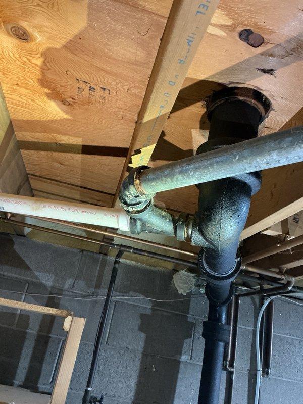 Responded to pre-sale home inspection findings regarding unsecured gas lines and corroded drainage fitting. Secured water heater gas line using two-hole straps and mounted furnace gas line with wall flange and split ring clamp. Cleaned minor surface rust from galvanized drain fitting joint. Gas lines were from previous installation completed three years prior and required proper mounting to meet code requirements.
