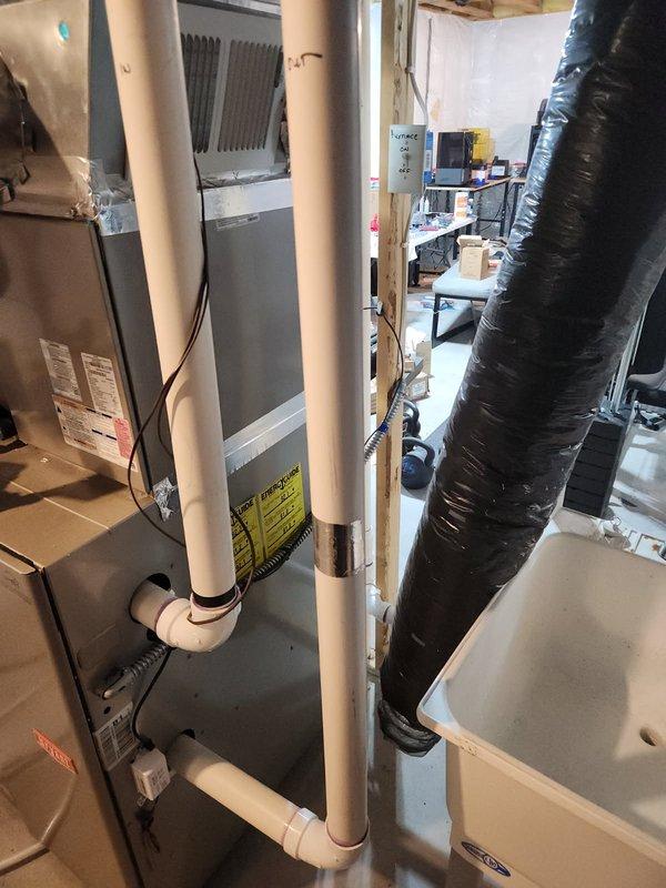 Responded to service call regarding disconnected insulated flexible ductwork hanging near furnace in basement following IAQ installation. Upon inspection, identified the hanging duct as an extra fresh air intake that was not part of the active HVAC system. Documented existing conditions with photographs showing the redundant intake ductwork, PVC condensate drainage system, furnace unit, and surrounding mechanical installations in the utility area.