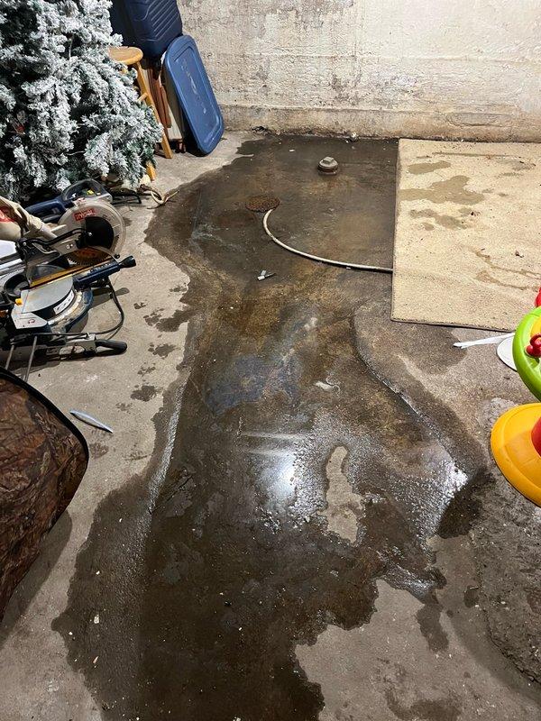 Responded to callback for AC unit installed 13 days prior with reported basement flooding from condensate drainage issue. Upon arrival, found significant water accumulation near furnace area with floor drain backing up and unable to handle discharge volume. Documented conditions with photos showing extensive water pooling on basement floor and compromised drainage system. Diagnosed clogged floor drain as primary cause preventing proper condensate removal. Scheduled plumber to snake drain line and advised that condensate pump installation with upstairs drain routing would be required if drain clearing unsuccessful.