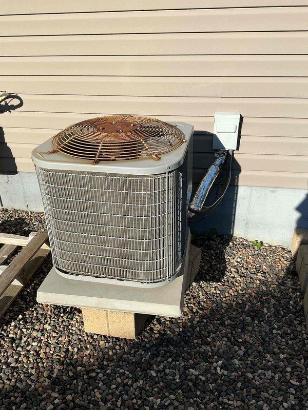 Responded to no-cooling complaint on 13-year-old system where customer reported hissing noise followed by loss of cooling capacity. Upon inspection, connected manifold gauges and found elevated system pressure but inadequate cooling performance. Verified clean air filter and proper airflow with no coil icing present. Tested filter dryer and attempted refrigerant charge adjustment with no improvement in system performance. Performed TXV diagnostic test by exposing sensing bulb to hot water with no change in suction pressure, then immersed bulb in ice water which caused pressure drop, indicating thermostatic expansion valve is closing properly but failing to open correctly. Diagnosis confirmed faulty TXV preventing proper refrigerant metering and system operation. Documented findings with photos of outdoor condensing unit installation. Provided customer with repair options and pricing for TXV replacement. Awaiting customer decision to proceed with recommended repairs.