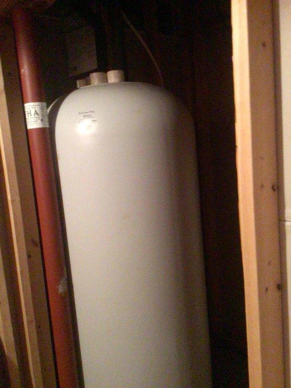 Responded to water leakage issue from 15-year-old HVAC system located in basement. Diagnosed and cleared clogged PVC elbow fitting at condensate drain line terminus, which was causing water overflow. Performed routine maintenance including replacement of air filter and AprilAire humidifier water panel as requested.
