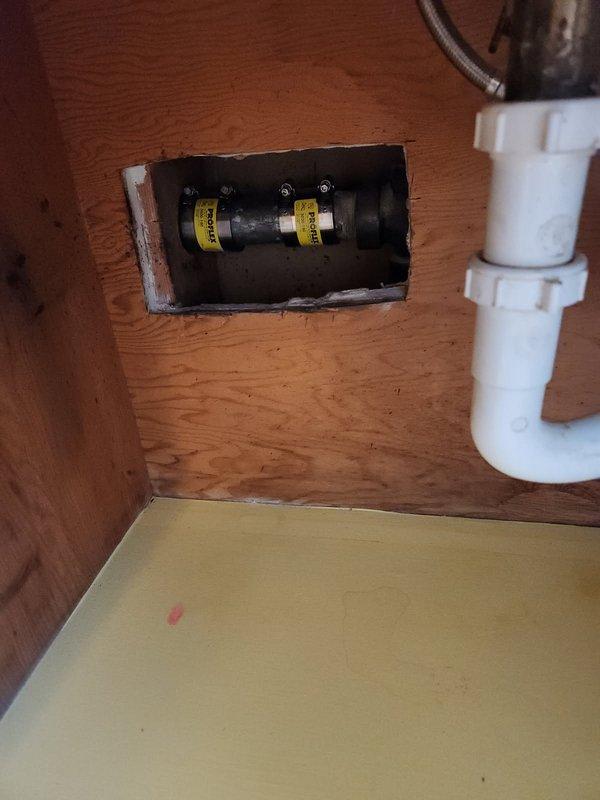 Completed repair of broken drain assembly under sink following previous drain cleaning service. Removed damaged drain components and installed new chrome P-trap assembly with proper slip-nut connections. Access required cutting rectangular opening in wooden cabinet panel to reach plumbing connections. Advised property owner on patching options for sheetrock access hole, including professional drywall repair or covering with access panel for future maintenance. All drain connections tested and verified leak-free with proper water flow restored to sink.