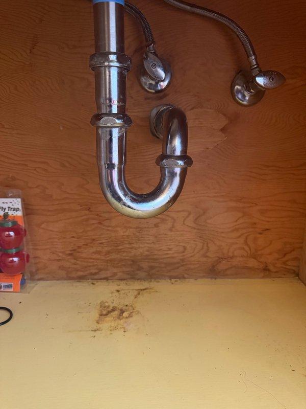Completed repair of broken drain assembly under sink following previous drain cleaning service. Removed damaged drain components and installed new chrome P-trap assembly with proper slip-nut connections. Access required cutting rectangular opening in wooden cabinet panel to reach plumbing connections. Advised property owner on patching options for sheetrock access hole, including professional drywall repair or covering with access panel for future maintenance. All drain connections tested and verified leak-free with proper water flow restored to sink.