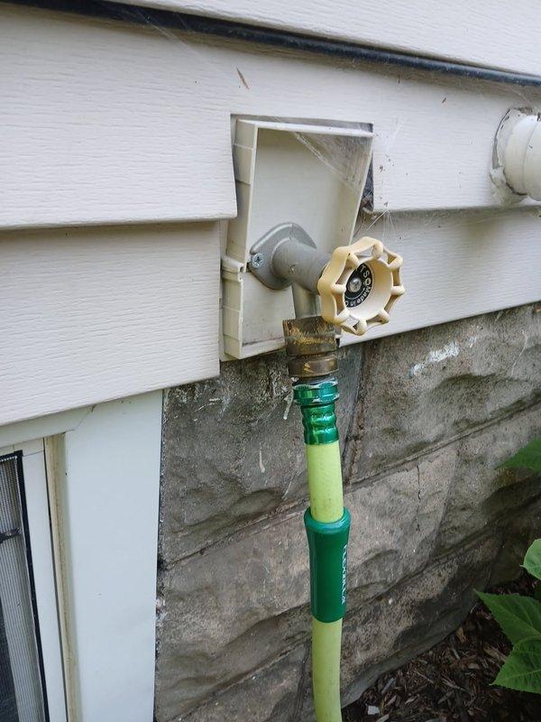 Responded to an active water leak at an exterior hose bibb mounted on the building's foundation. Upon arrival, confirmed heavy leaking from the outdoor spigot as reported. Removed the failed hose bibb assembly from the exterior wall and installed a new replacement unit, ensuring proper seal against the vinyl siding and foundation interface. Tested the new hose bibb for proper operation and verified no leaks were present after installation.