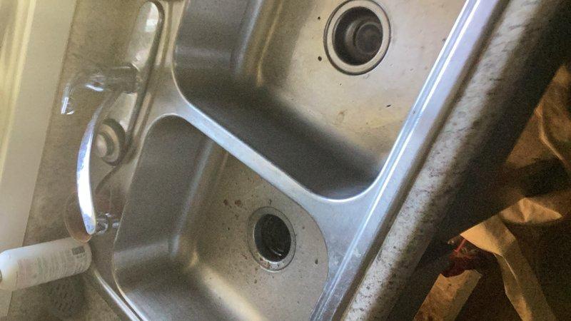 Responded to service call for slow-draining kitchen sink with suspected garbage disposal malfunction. Upon inspection, determined the two-inch drain line was severely clogged, causing water to back up in both basins of the double-basin stainless steel sink. Snaked the kitchen drain line three times to clear the obstruction and restore proper drainage. Verified garbage disposal remained in working order and did not require replacement.