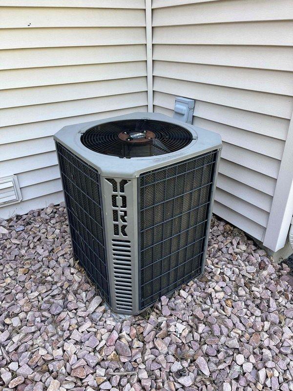 Responded to no cooling complaint on 10+ year old York system where indoor blower motor would not operate. Diagnosed AC unit running briefly before shutting down, causing both outdoor unit and indoor blower to cease operation without tripping low-voltage fuse. Systematically tested components and isolated issue to outdoor unit by disconnecting it from furnace, confirming indoor blower operated normally when separated. Further testing identified faulty crankcase heater causing system shutdown. Disconnected defective crankcase heater from contactor, restoring full system operation. System currently running and cooling properly with crankcase heater isolated. Submitted parts pricing request and recommended system replacement due to age and condition of equipment.
