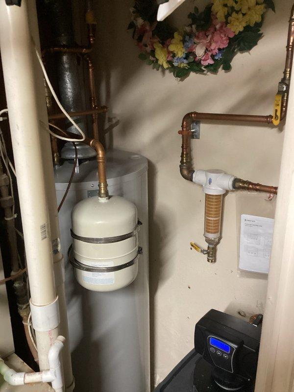 Responded to service call regarding persistent salty taste in water following water softener regeneration cycles. Performed water hardness testing at multiple fixtures, measuring 20 grains at kitchen cold tap and 0 grains at bathroom cold tap. Adjusted softener regeneration cycle parameters by increasing flush times by several minutes to allow complete brine tank drainage and prevent premature valve closure that was causing residual salt to enter the distribution system.