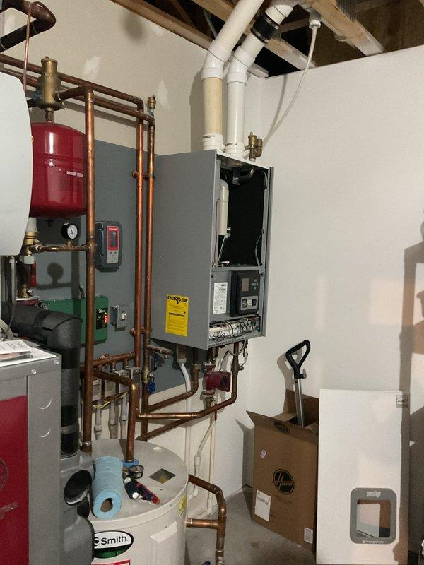 Performed second opinion inspection of geothermal system with Trinity boiler backup and associated hydronic components. Evaluated system following customer concerns regarding previous service work quality, including water intrusion in furnace cabinet and visible calcification on piping. Inspected boiler piping connections, circulation pump, expansion tank, and PVC exhaust venting. Examined fresh air intake piping experiencing condensation dripping issues; confirmed temporary cap solution appropriate given negative pressure conditions in structure. Advised removal of intake cap prior to heating season. Observed copper piping with evidence of previous repairs including patched penetrations. Documented water heater and water treatment system integration with heating system. Recommended follow-up service appointment during cooler weather to perform complete system evaluation and maintenance on geothermal unit when not under active cooling load demand.