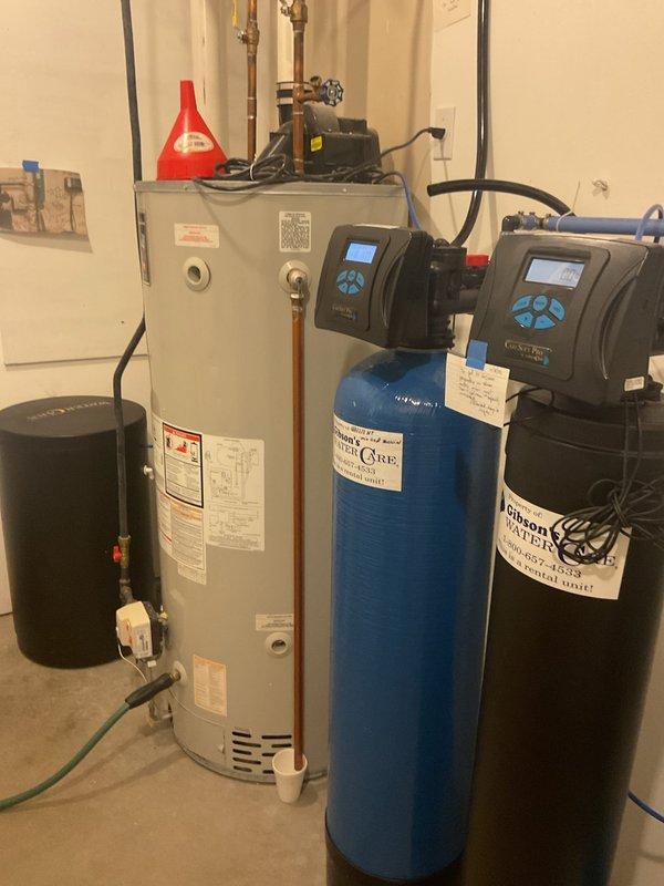 Performed second opinion inspection of geothermal system with Trinity boiler backup and associated hydronic components. Evaluated system following customer concerns regarding previous service work quality, including water intrusion in furnace cabinet and visible calcification on piping. Inspected boiler piping connections, circulation pump, expansion tank, and PVC exhaust venting. Examined fresh air intake piping experiencing condensation dripping issues; confirmed temporary cap solution appropriate given negative pressure conditions in structure. Advised removal of intake cap prior to heating season. Observed copper piping with evidence of previous repairs including patched penetrations. Documented water heater and water treatment system integration with heating system. Recommended follow-up service appointment during cooler weather to perform complete system evaluation and maintenance on geothermal unit when not under active cooling load demand.